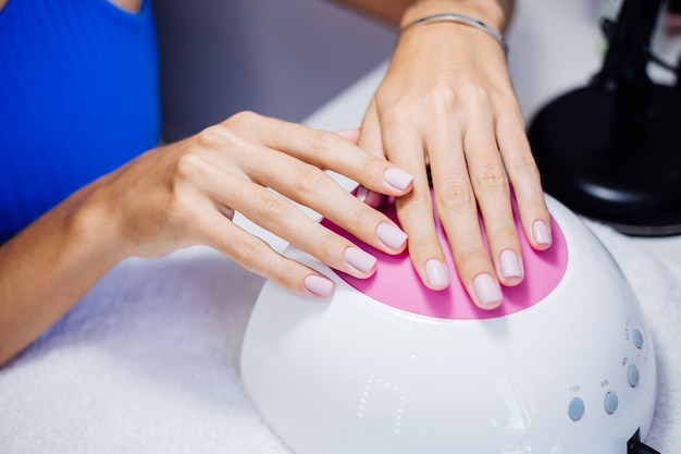 Proceso de fabricación de tratamiento de uñas de manos femeninas hermosas Taladro de lima de uñas profesional en acción Concepto de cuidado de la belleza y las manos