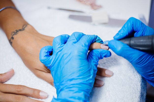Proceso de fabricación de tratamiento de uñas de manos femeninas hermosas Taladro de lima de uñas profesional en acción Concepto de cuidado de la belleza y las manos