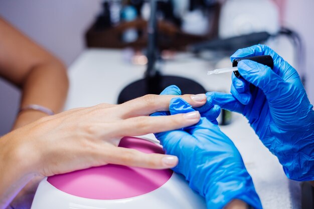 Proceso de fabricación de tratamiento de uñas de manos femeninas hermosas Taladro de lima de uñas profesional en acción Concepto de cuidado de la belleza y las manos