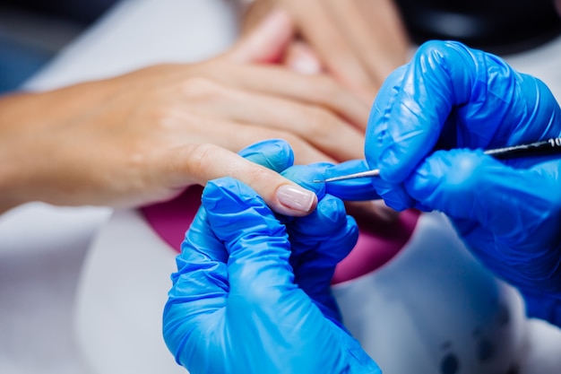 Proceso de fabricación de tratamiento de uñas de manos femeninas hermosas Taladro de lima de uñas profesional en acción Concepto de cuidado de la belleza y las manos