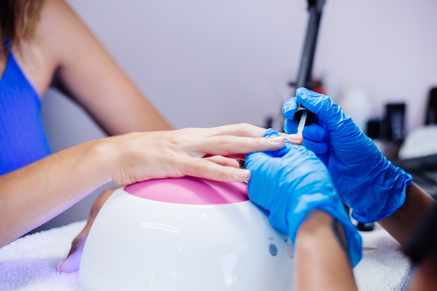 Proceso de fabricación de tratamiento de uñas de manos femeninas hermosas Taladro de lima de uñas profesional en acción Concepto de cuidado de la belleza y las manos