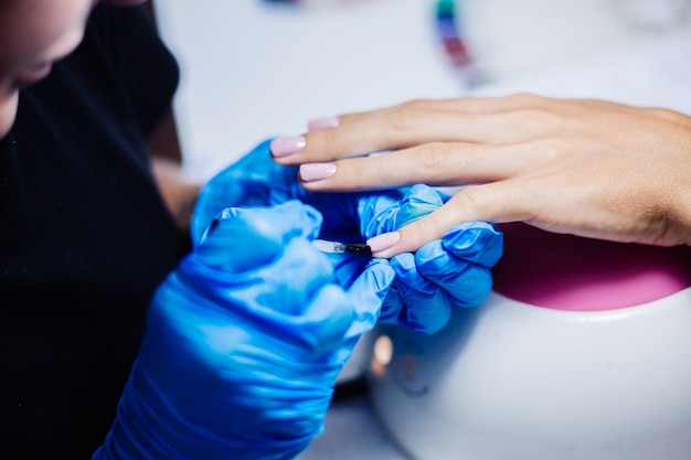 Proceso de fabricación de tratamiento de uñas de manos femeninas hermosas Taladro de lima de uñas profesional en acción Concepto de cuidado de la belleza y las manos