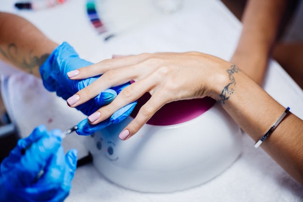 Proceso de fabricación de tratamiento de uñas de manos femeninas hermosas Taladro de lima de uñas profesional en acción Concepto de cuidado de la belleza y las manos