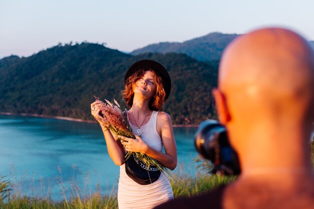 Proceso de grabación de video Hombre tomar un video en cámara profesional de blogger joven y elegante en vacaciones vista tropical