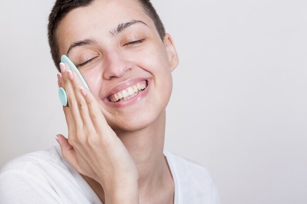 Proceso de limpieza de cara de mujer sonriente