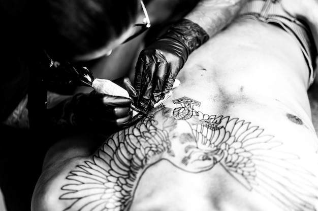Foto gratuita proceso de salón de tatuajes. una chica tatuadora rellenó un tatuaje. el proceso de rellenar un tatuaje en el cuerpo. primer plano de las manos.