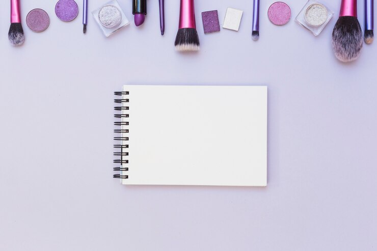Foto gratuito producto de cosméticos sobre bloc de notas en blanco espiral sobre fondo púrpura