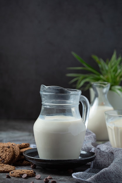 Productos lácteos sabrosos productos lácteos saludables en una mesa de crema agria en un tazón, tazón de requesón, crema en un banco y tarro de leche, botella de vidrio y en un vaso.