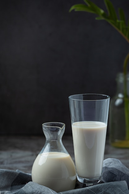 Productos lácteos sabrosos productos lácteos saludables en una mesa de crema agria en un tazón, tazón de requesón, crema en un banco y tarro de leche, botella de vidrio y en un vaso.