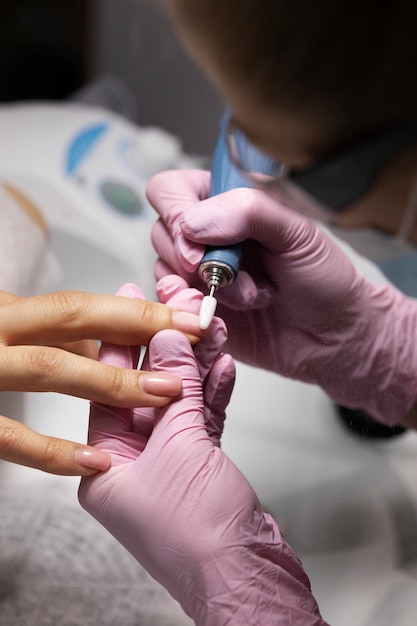 Profesional del arte de las uñas trabajando en las uñas de los clientes