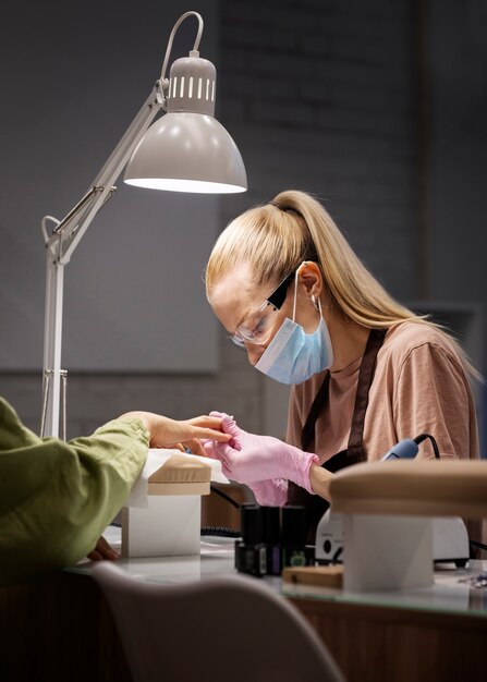 Profesional del arte de las uñas trabajando en las uñas de los clientes