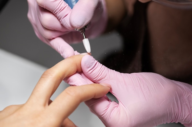 Profesional del arte de las uñas trabajando en las uñas de los clientes