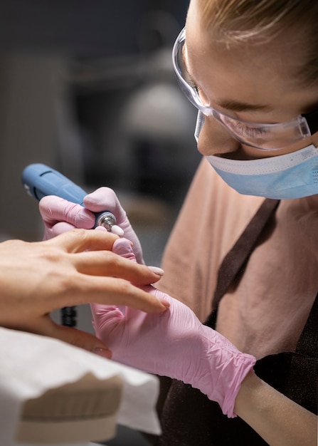 Profesional del arte de las uñas trabajando en las uñas de los clientes