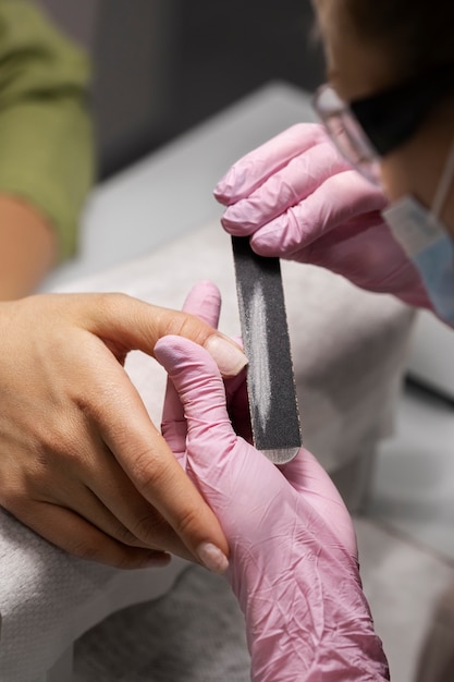 Profesional del arte de las uñas trabajando en las uñas de los clientes