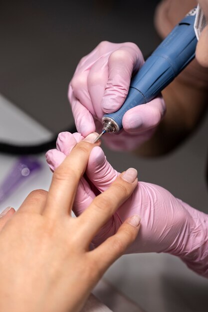 Profesional del arte de las uñas trabajando en las uñas de los clientes