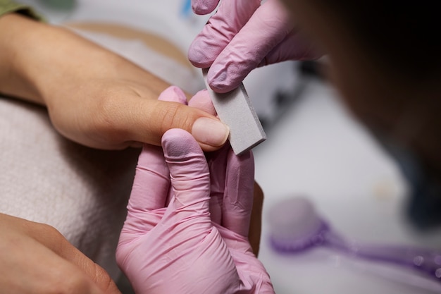 Profesional del arte de las uñas trabajando en las uñas de los clientes