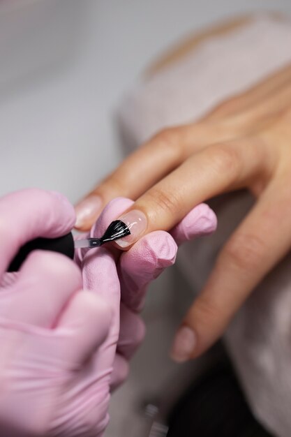 Profesional del arte de las uñas trabajando en las uñas de los clientes