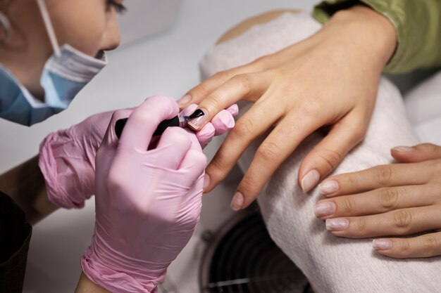 Profesional del arte de las uñas trabajando en las uñas de los clientes