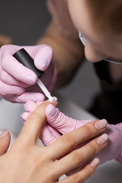 Profesional del arte de las uñas trabajando en las uñas de los clientes