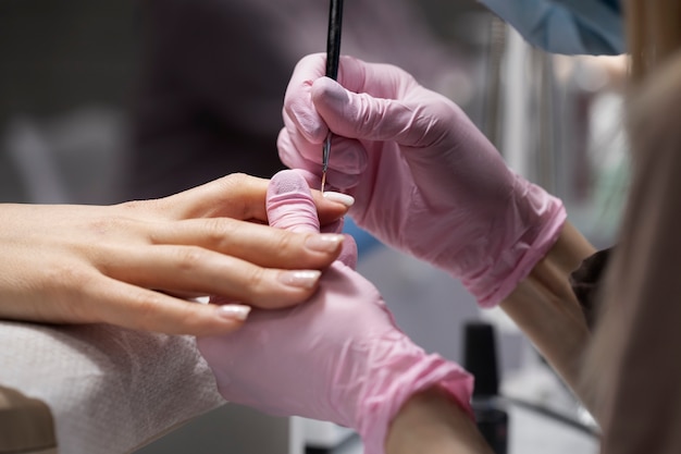 Profesional del arte de las uñas trabajando en las uñas de los clientes