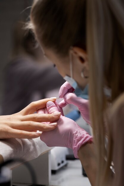 Profesional del arte de las uñas trabajando en las uñas de los clientes