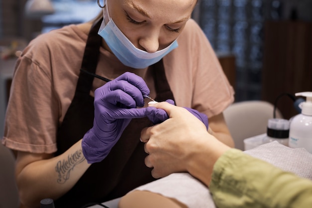 Profesional del arte de las uñas trabajando en las uñas de los clientes