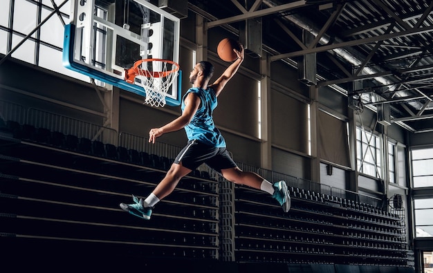 Foto gratuita profesional negro jugador de baloncesto negro en acción en una cancha de baloncesto.