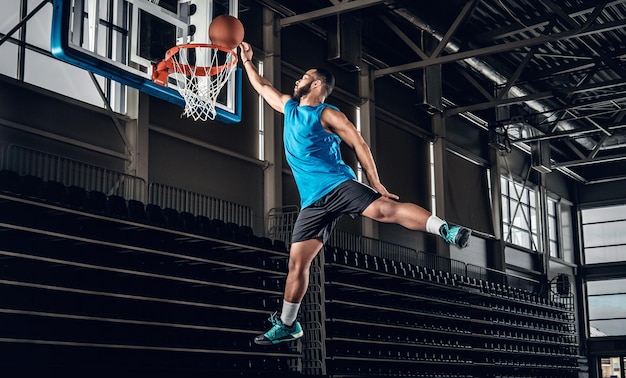 Foto gratuita profesional negro jugador de baloncesto negro en acción en una cancha de baloncesto.