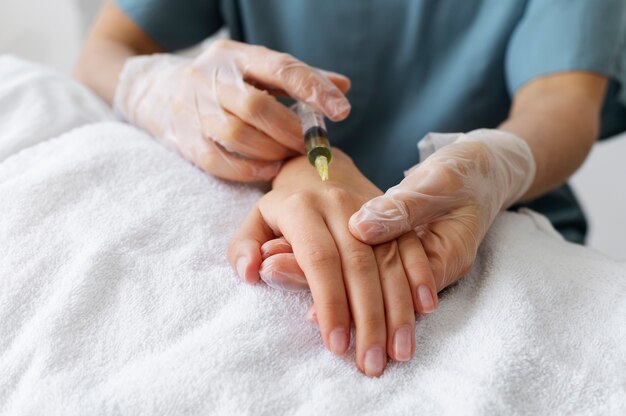 Profesional de la salud de ángulo bajo que inyecta la mano