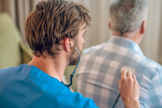 Foto gratuita profesional sanitario caucásico auscultando a un hombre canoso