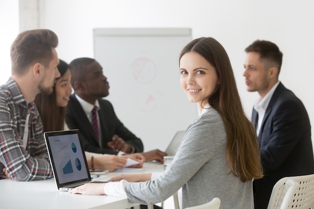 Profesional sonriente o interno de la empresaria que mira la cámara en la reunión