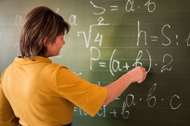 Profesor de alto ángulo escribiendo en la pizarra