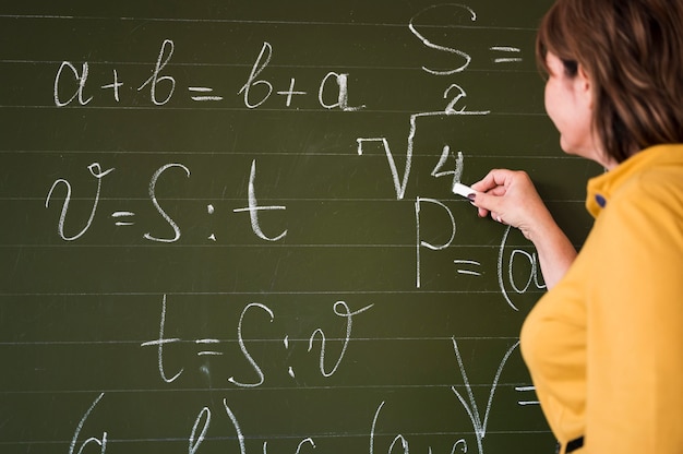 Profesor de ángulo bajo escribiendo en la pizarra