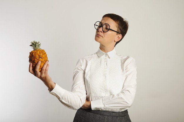 Foto gratuita profesor de aspecto loco en traje conservador mirando inquisitivamente una piña aislada en blanco