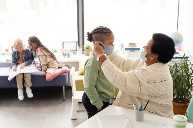 Profesor ayudando a un estudiante a ponerse una mascarilla médica