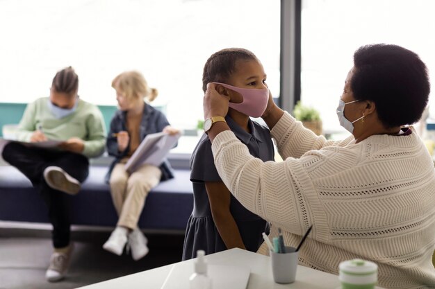 Profesor ayudando a un estudiante a ponerse una mascarilla médica