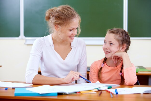 Profesor ayudando a la niña con la lección de escritura