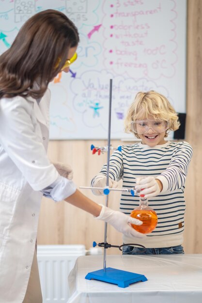 Profesor ayudando a un niño a poner un matraz en un trípode