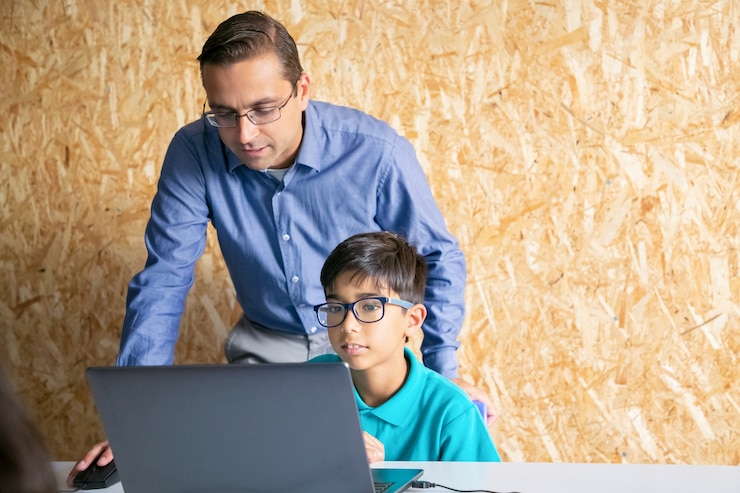 Foto gratuito profesor de contenido de mediana edad ayudando al niño con la lección y explicando el tema