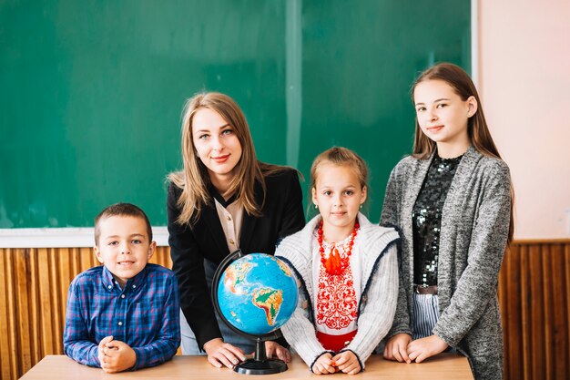 Profesor de escuela femenina y estudiantes de pie con globo