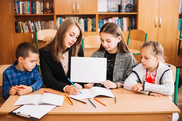 Profesor de la escuela trabajando con los alumnos en el escritorio