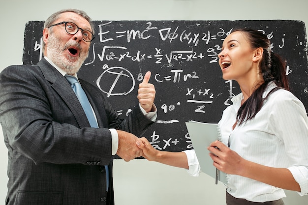 Profesor masculino y joven contra la pizarra en el aula