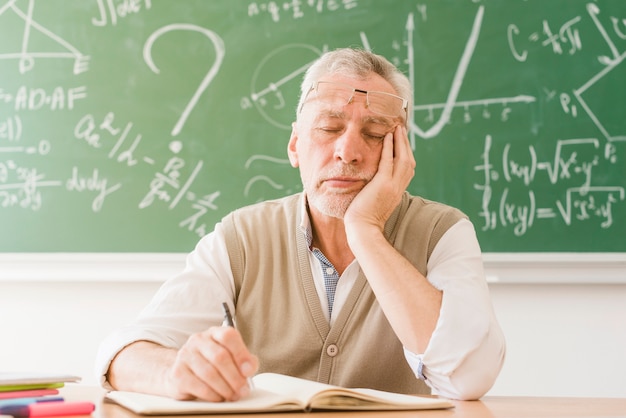 Foto gratuita profesor de matemáticas envejecido cansado que duerme en el escritorio