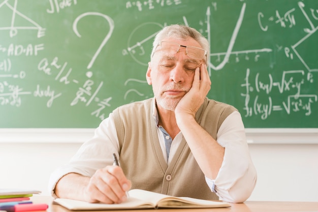 Profesor de matemáticas envejecido cansado que duerme en el escritorio