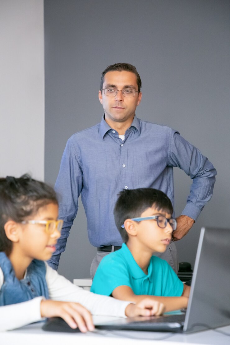 Foto gratuito profesor de mediana edad con experiencia observando a los estudiantes