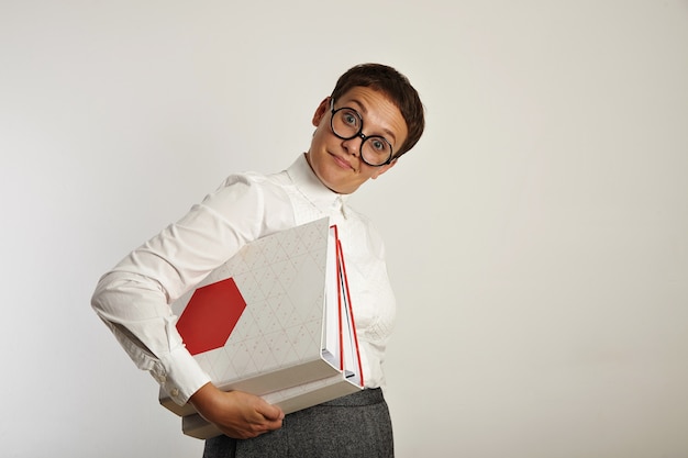 Foto gratuita profesor de mujer divertida sorprendida inquisitivamente y sostiene dos carpetas de documentos grandes con un nuevo plan educativo