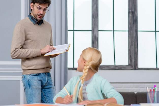 Profesor de pie y niño escuchándolo