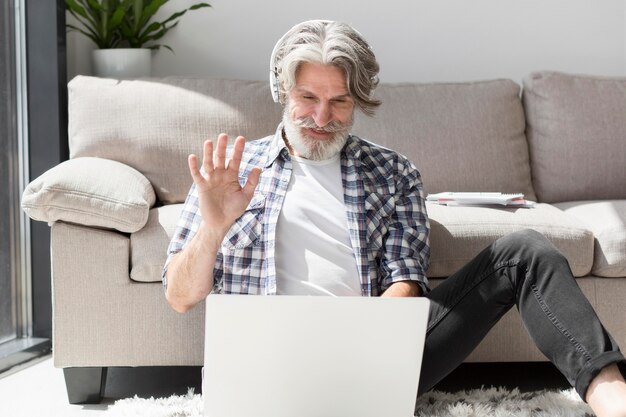 Profesor en piso saludando a laptop