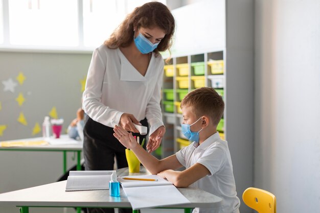 Profesor de plano medio tomando la temperatura de un alumno