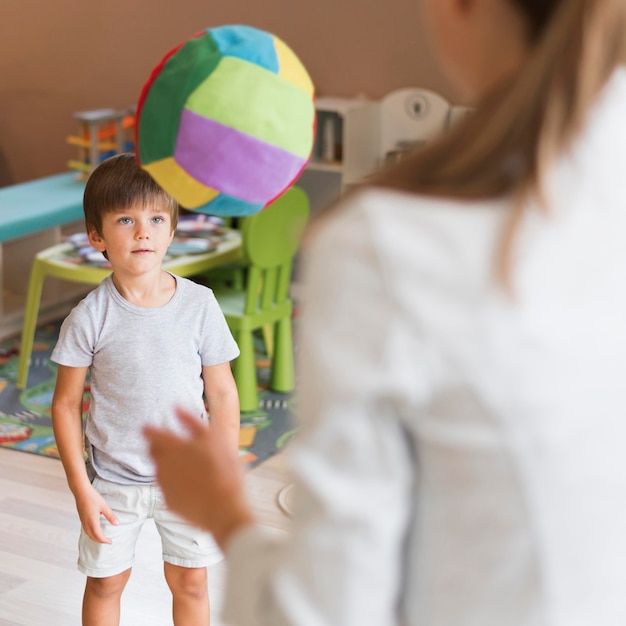 Profesor de primer plano y niño jugando con pelota